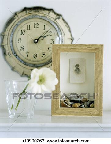 Stock Photo - Close-up of old clock on wall above wooden box frame and white flower. Fotosearch