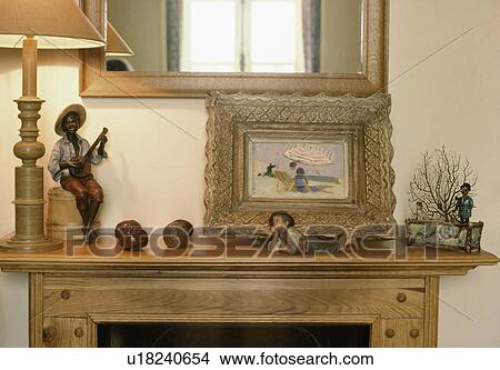 Close-up of old gilt-framed picture and blackamoor ornaments on pine mantelpiece View Large Photo Image Picture - Close-up of old gilt-framed picture and blackamoor ornaments on pine mantelpiece. Fotosearch