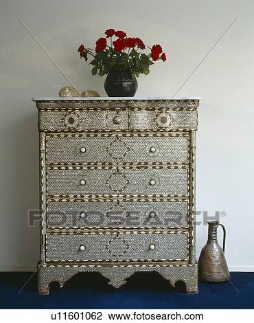 Stock Image - Close-up of ornate metallic chest-of-drawers. Fotosearch