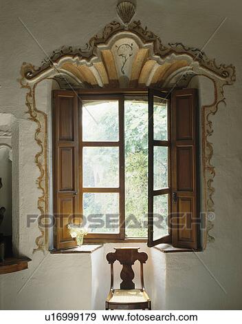 Stock Photo - Close-up of ornate rococo plasterwork above window with wooden shutters. Fotosearch