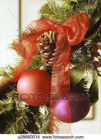 Stock Photography - Close-up of red and pink glass Christmas tree baubles tied with red ribbon. Fotosearch