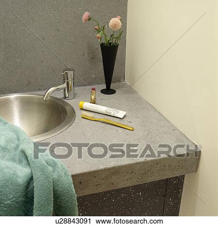 Stock Image - Close-up of stainless steel tap and basin in concrete vanity unit. Fotosearch