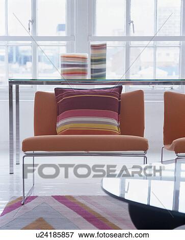Stock Photo - Close-up of striped cushion on modern upholstered orange chair. Fotosearch