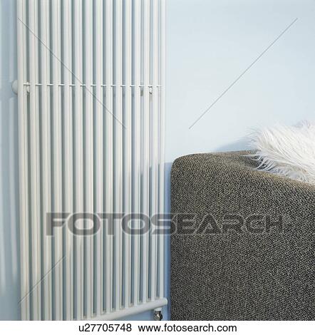 Stock Photo - Close up of vertical white metal radiator in modern living room. Fotosearch