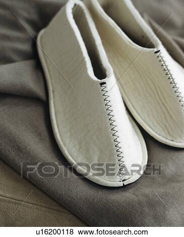 Stock Photo - Close-up of white felt slippers on grey fabric. Fotosearch