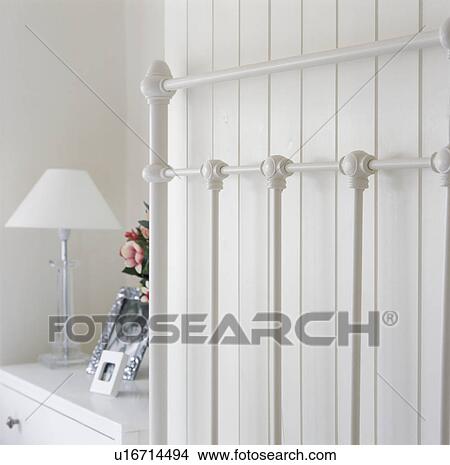 Close-up of white iron bed against white panelled wall View Large Photo Image Picture - Close-up of white iron bed against white panelled wall. Fotosearch