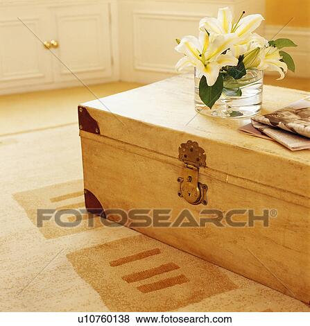 Stock Photo - Close-up of white lilies in glass vase on large wooden chest. Fotosearch