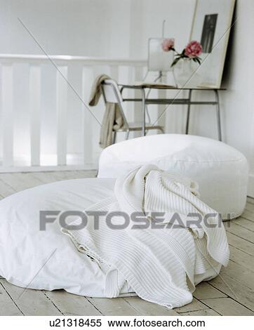 Stock Photography - Close-up of white wool rug and large white floor-cushions. Fotosearch
