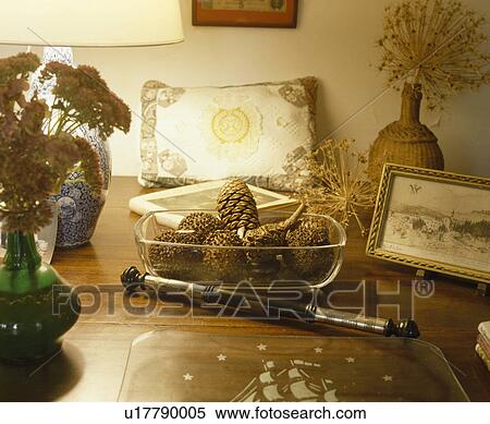 Stock Photography - Close-up pine cones in glass dish on table with antique pen. Fotosearch