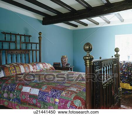 Colourful patchwork quilt on antique bed in blue country bedroom with beamed ceiling View Large Photo Image Stock Image - Colourful patchwork quilt on antique bed in blue country bedroom with beamed ceiling. Fotosearch