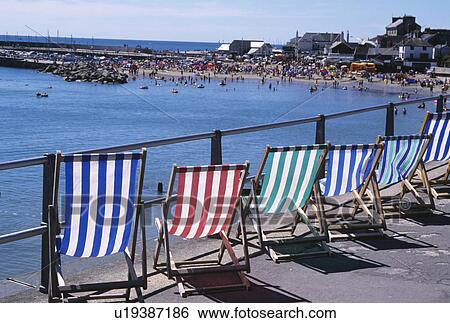 Stock Photograph - Colourful striped deckchairs on the promenade above the sea at Lyme Regis in Dorset. Fotosearch