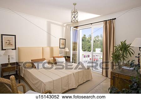Stock Image - Comfortable bedroom overlooking terrace and beyond.. Fotosearch