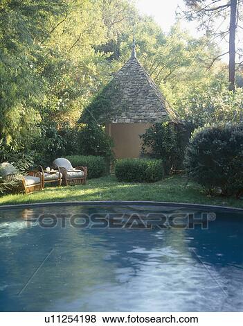 Comfy chairs on grass beside natural pool and stone pavilion View Large Photo Image Stock Photo - Comfy chairs on grass beside natural pool and stone pavilion . Fotosearch