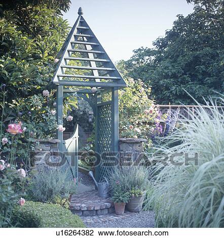 Conical wooden decoration on gate in small garden with lavender growing in pots and blue-grey grasses View Large Photo Image Stock Image - Conical wooden decoration on gate in small garden with lavender growing in pots and blue-grey grasses . Fotosearch