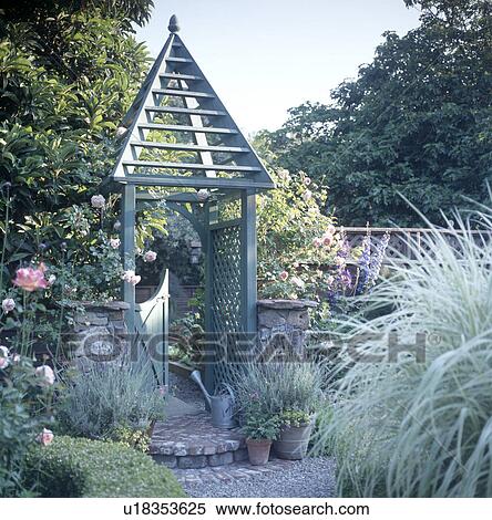 Conical wooden decoration on gate in small garden with lavender growing in pots and blue-grey grasses View Large Photo Image Stock Photography - Conical wooden decoration on gate in small garden with lavender growing in pots and blue-grey grasses . Fotosearch