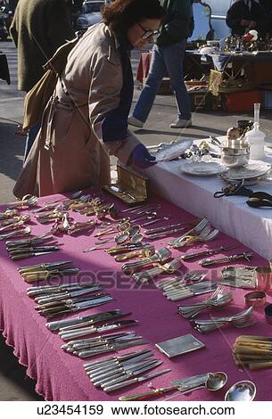 Stock Photo - Customer looking at old cutlery displayed on stall in street market in Paris. Fotosearch