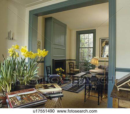 Stock Image - Daffodils on table beside double doorway to traditional dining room. Fotosearch