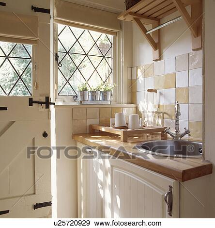 Drainer on beech worktop with built in circular stainless steel sink beside lattice window in cream cottage kitchen View Large Photo Image Stock Photo - Drainer on beech worktop with built in circular stainless steel sink beside lattice window in cream cottage kitchen. Fotosearch