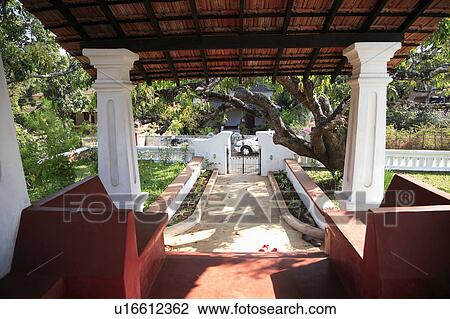 Stock Image - Entrance from green gate up the path to the veranda, which has seating under a canopy.. Fotosearch