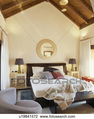 Faux fur throw on bed in modern country bedroom with beamed apex ceiling View Large Photo Image Stock Image - Faux fur throw on bed in modern country bedroom with beamed apex ceiling. Fotosearch