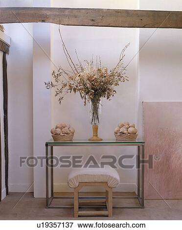 Floral arrangement on modern glass-topped table in white hall View Large Photo Image Stock Photo - Floral arrangement on modern glass-topped table in white hall. Fotosearch