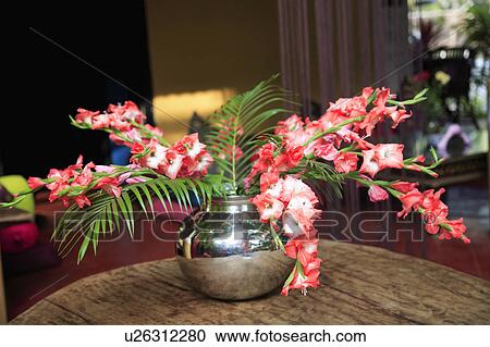 Stock Image - Flower arrangement in silver vase on table.. Fotosearch