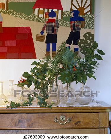 Stock Photo - Fresh foliage in glass vases with collection of glass carafes below applique picture. Fotosearch