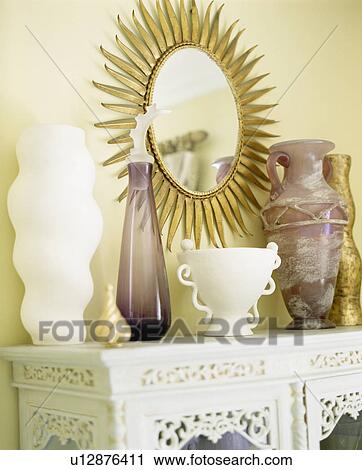 Gilt sunburst mirror above ceramic and glass vases on fretwork table View Large Photo Image Stock Image - Gilt sunburst mirror above ceramic and glass vases on fretwork table. Fotosearch