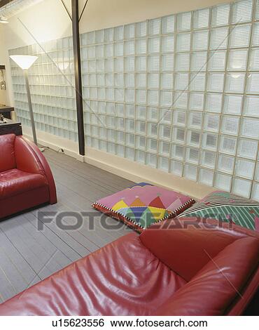 Glass brick wall in modern living room with colourful floor cushions and red leather sofas View Large Photo Image Stock Photograph - Glass brick wall in modern living room with colourful floor cushions and red leather sofas. Fotosearch