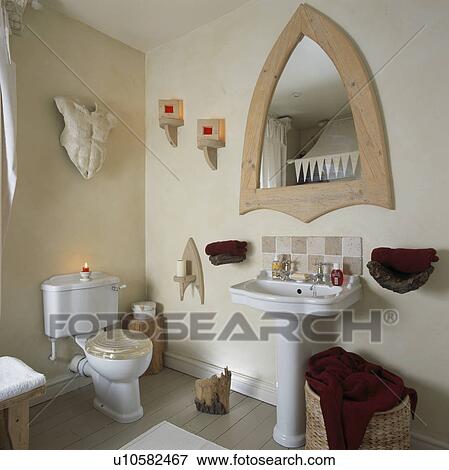 Stock Photo - Gothic mirror above white pedestal basin in small bathroom with sculpture on wall. Fotosearch