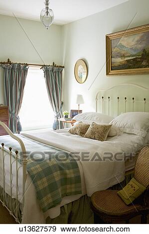 Gren+white checked throw and white quilt on white iron bed in country bedroom View Large Photo Image Stock Photo - Gren+white checked throw and white quilt on white iron bed in country bedroom. Fotosearch