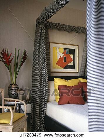 Grey drapes and yellow and red cushions on modern four-poster bed View Large Photo Image Stock Photo - Grey drapes and yellow and red cushions on modern four-poster bed. Fotosearch