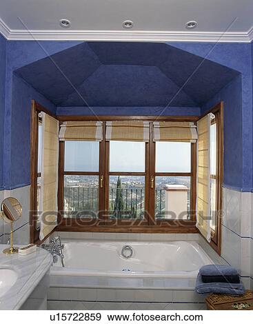 Large bath in front of window in blue Spanish bathroom View Large Photo Image Stock Photo - Large bath in front of window in blue Spanish bathroom. Fotosearch