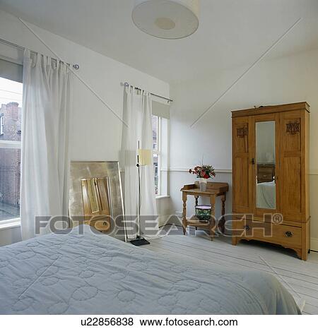 Large wardrobe with mirrored door in townhouse bedroom with white curtains View Large Photo Image Stock Photo - Large wardrobe with mirrored door in townhouse bedroom with white curtains. Fotosearch