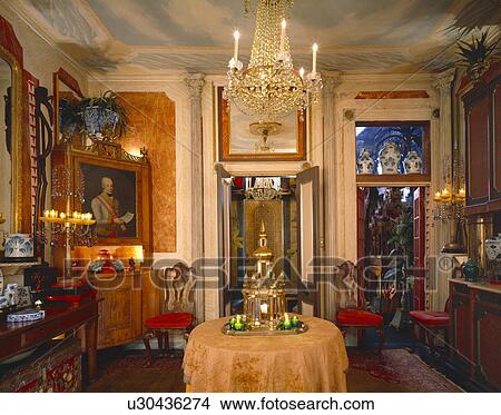 Lighted glass chandelier above table in opulent dining room with antique furniture View Large Photo Image Picture - Lighted glass chandelier above table in opulent dining room with antique furniture. Fotosearch