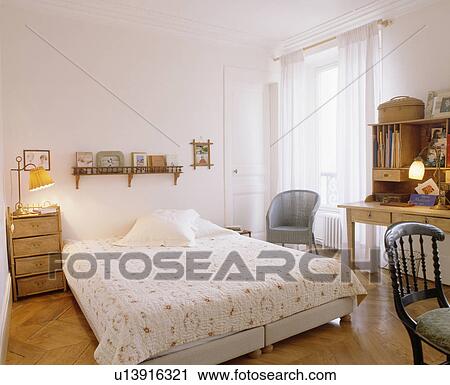 Lighted lamp on bedside table beside divan bed with patterned white quilt View Large Photo Image Stock Image - Lighted lamp on bedside table beside divan bed with patterned white quilt. Fotosearch