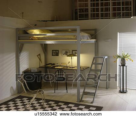 Lighted lamp on desk below bed on metal platform with ladder in modern teenager's bedroom View Large Photo Image Stock Image - Lighted lamp on desk below bed on metal platform with ladder in modern teenager's bedroom. Fotosearch