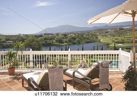 Loungers on terrace overlooking lake and golf course. View Large Photo Image Stock Image - Loungers on terrace overlooking lake and golf course.. Fotosearch