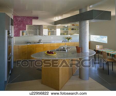 Low-ceilinged modern openplan kitchen with boomerang-shaped island with two sinks in granite worktop View Large Photo Image Stock Image - Low-ceilinged modern openplan kitchen with boomerang-shaped island with two sinks in granite worktop. Fotosearch