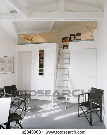 Metal ladder to platform bed in modern white attic living and dining room with black chairs View Large Photo Image Stock Image - Metal ladder to platform bed in modern white attic living and dining room with black chairs. Fotosearch