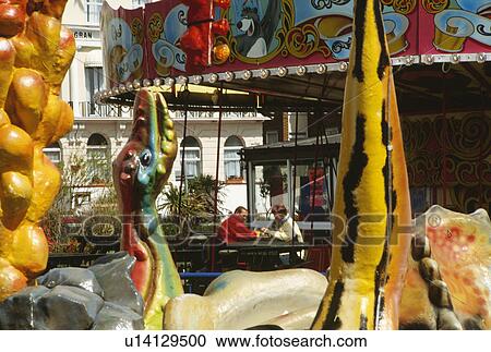 Stock Image - Middleaged couple seen through colourful fairground figures. Fotosearch