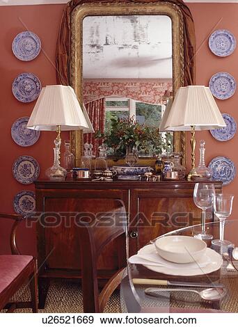 Mirror above lamps on antique sideboard in pink dining room View Large Photo Image Stock Photo - Mirror above lamps on antique sideboard in pink dining room. Fotosearch