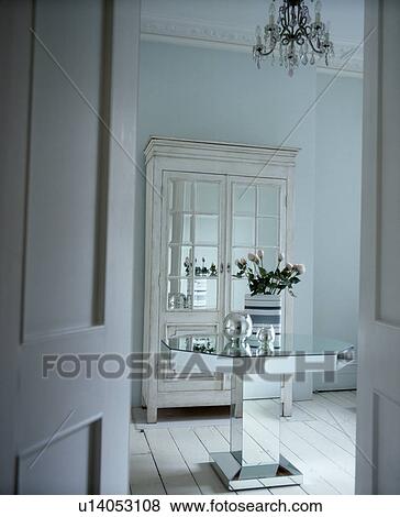 Stock Photo - Mirrored glass table and white cupboard in white dining room. Fotosearch
