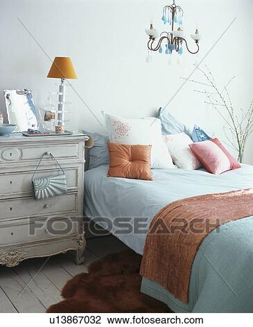 Stock Image - Modern bedroom with turquoise bedlinen on bed with orange throw and cushion. Fotosearch