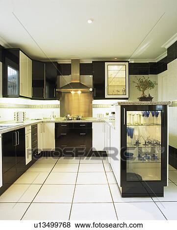 Stock Photo - Modern black and white kitchen with white ceramic tiled floor. Fotosearch