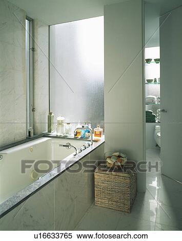 Modern compact white bathroom with marble-tiled bath panel View Large Photo Image Stock Photography - Modern compact white bathroom with marble-tiled bath panel. Fotosearch