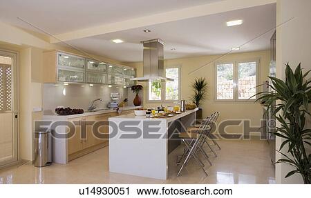 Modern light kitchen with illuminated wall cupboards, central hob and extractor. View Large Photo Image Stock Image - Modern light kitchen with illuminated wall cupboards, central hob and extractor.. Fotosearch