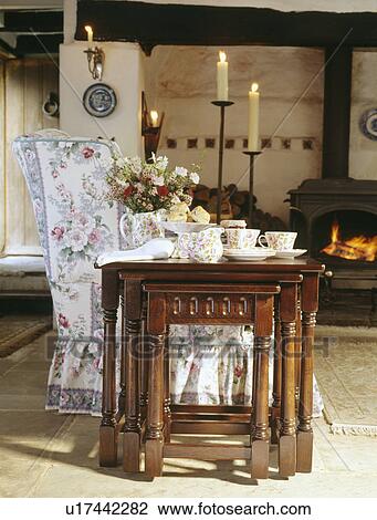 Oak nest-of-tables beside floral sofa in cottage living room View Large Photo Image Stock Image - Oak nest-of-tables beside floral sofa in cottage living room. Fotosearch