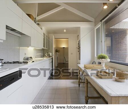 Old marble-topped table below window with slatted blind in modern white kitchen with white tiled floor View Large Photo Image Stock Image - Old marble-topped table below window with slatted blind in modern white kitchen with white tiled floor. Fotosearch