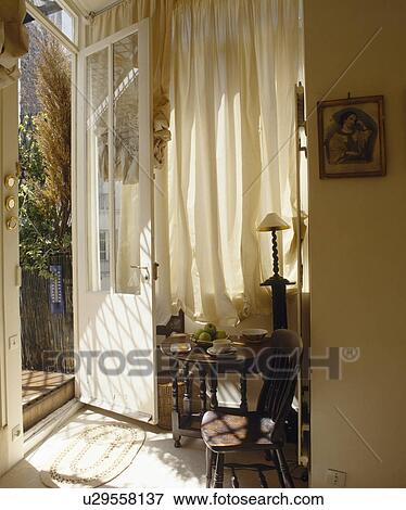 Old wooden chair and table in front of cream curtain in hall with open door View Large Photo Image Stock Photo - Old wooden chair and table in front of cream curtain in hall with open door. Fotosearch